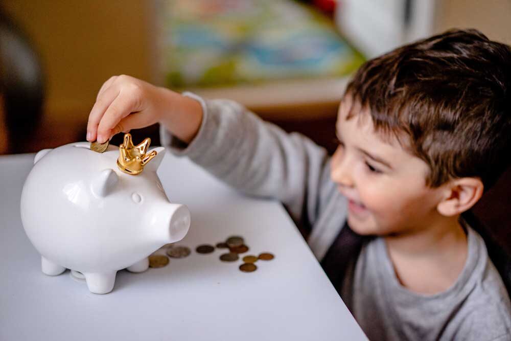 boy putting money into piggy bank